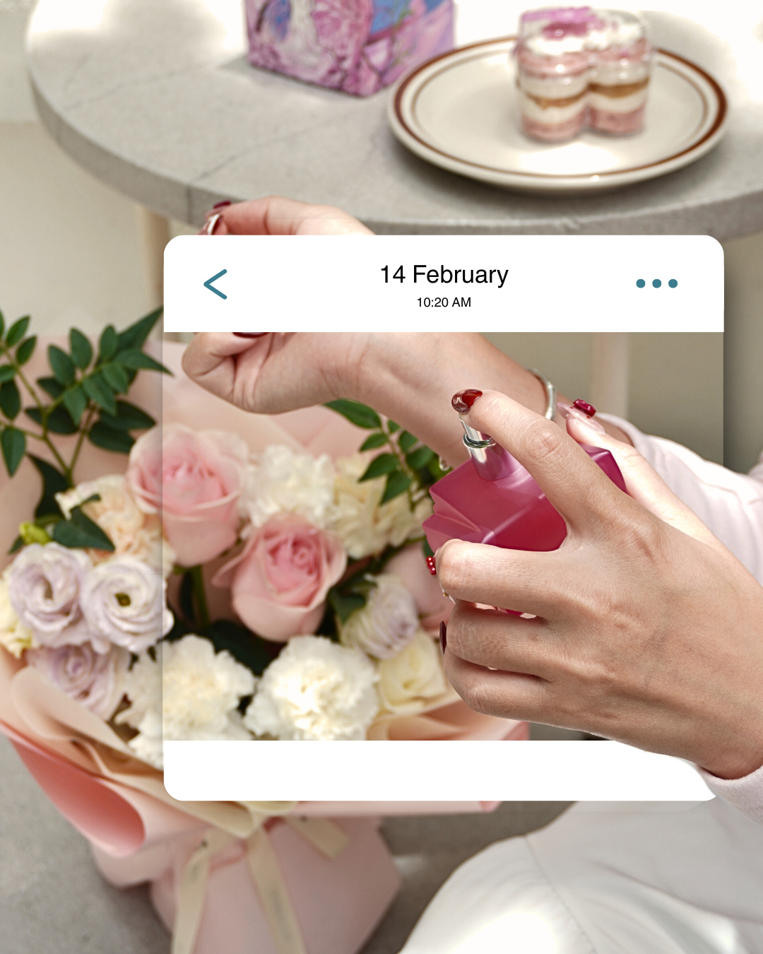 A hand spraying a pink perfume bottle in front of a bouquet of roses and carnations, inside a '14 February' message card (slide 3 of 4)